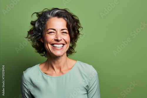 Portrait of a happy middle aged woman smiling against a green background