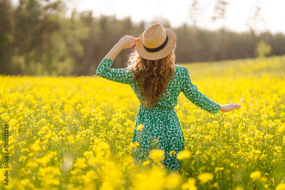 Beautiful woman walking in the blooming field at sunny summer day. Nature, vacation, relax and lifestyle. Summer landscape.