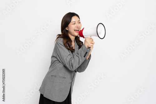 Young Asian businesswoman in grey suit smile and holding megaphone isolated on white background, Wow and Announce Speech concept