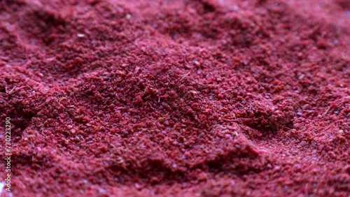 Red sumac spice powder falling down close up photo