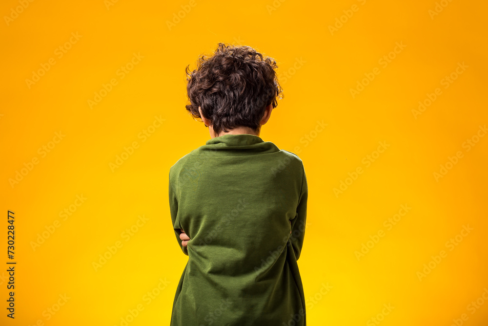 Sad child boy standing with his back turned to the camera. Negative emotions concept Sad child boy standing with his back turned to the camera. Negative emotions concept