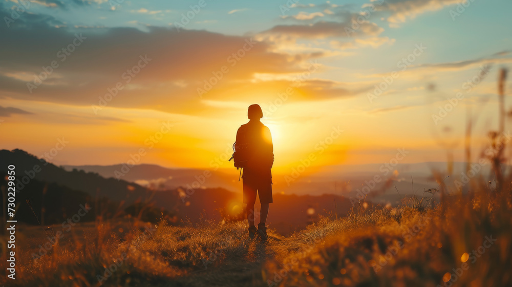 A young hipster hiking in beautiful hills and meadows of the Black Forest in summer at sunset