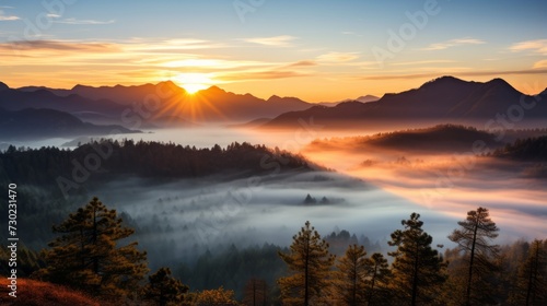 The sun is setting over a foggy mountain range