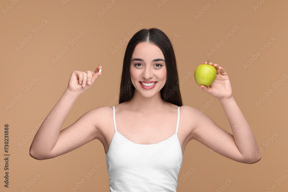 Beautiful young woman with vitamin pill and apple on beige background Beautiful young woman with vitamin pill and apple on beige background