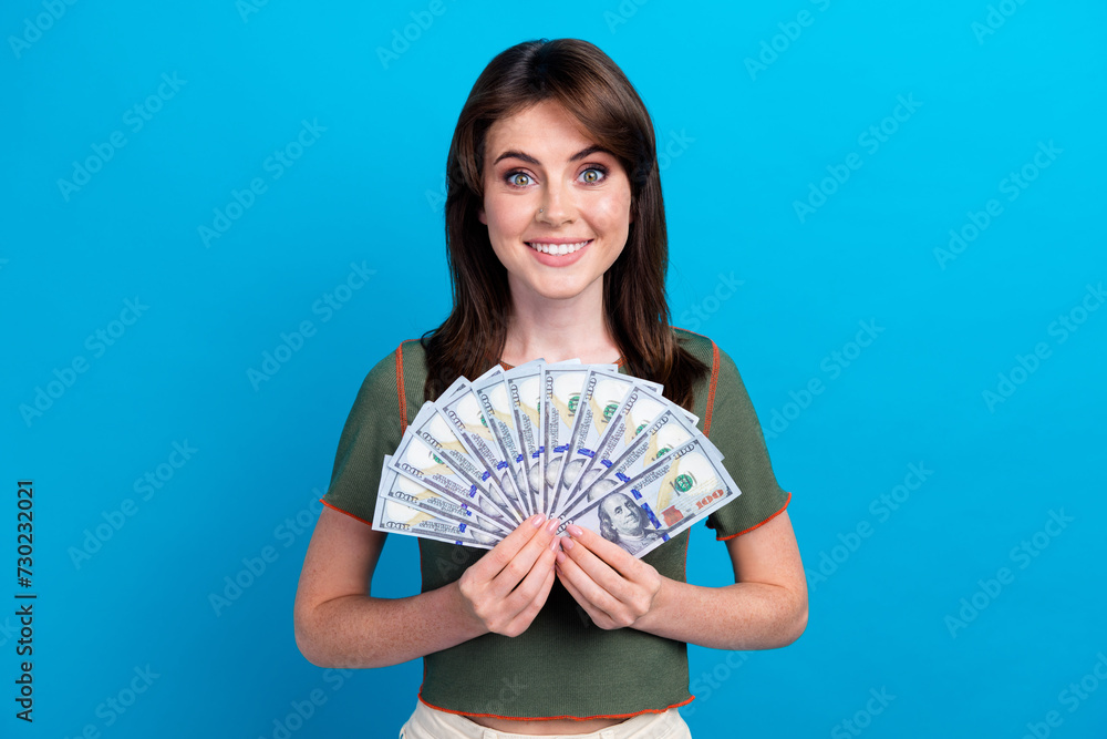 Portrait of cheerful gorgeous girl toothy smile hands hold dollar bills banknotes isolated on blue color background Portrait of cheerful gorgeous girl toothy smile hands hold dollar bills banknotes isolated on blue color background
