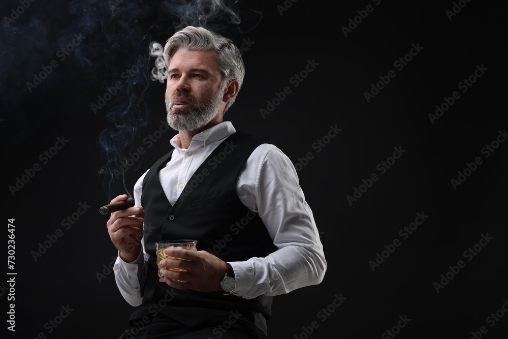 Bearded man with glass of whiskey smoking cigar against black background. Space for text Bearded man with glass of whiskey smoking cigar against black background. Space for text