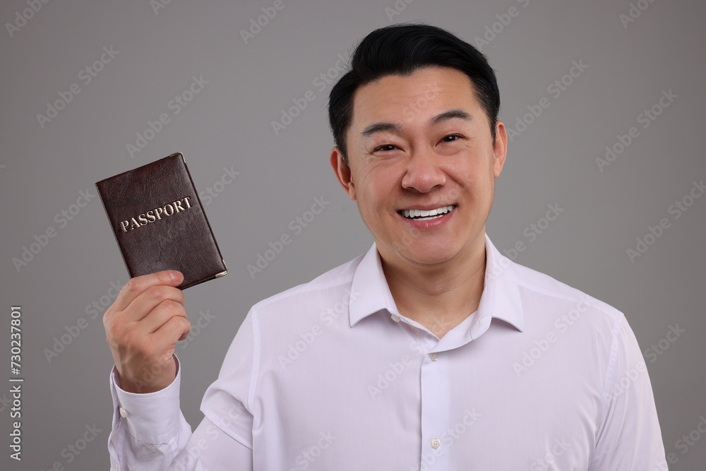 Immigration. Happy man with passport on grey background Immigration. Happy man with passport on grey background