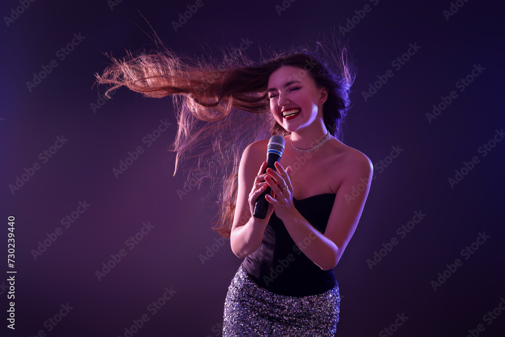 Emotional woman with microphone singing in neon lights on dark background Emotional woman with microphone singing in neon lights on dark background
