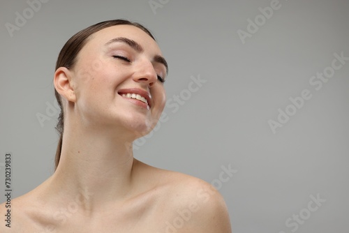 Portrait of smiling woman on grey background. Space for text