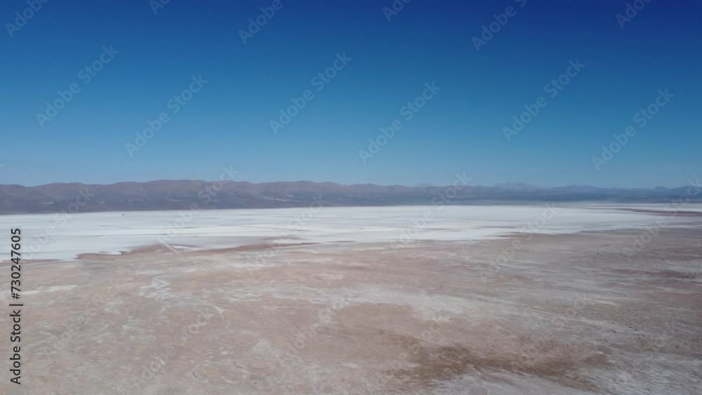 Camera slowly panning across big white salt pan with light brown soil around the pan Camera slowly panning across big white salt pan with light brown soil around the pan