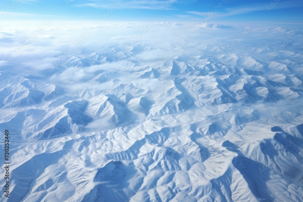 Fototapeta premium Aerial view of a mountainous terrain covered in a blanket of snow