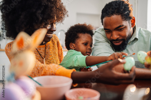 Canvas Print Close up of interracial family sits together at easter and painting eggs