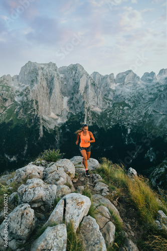An extreme sportswoman is skyrunning on rocky mountain.