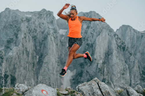 An extreme sportswoman is running and jumping on rocky mountains.