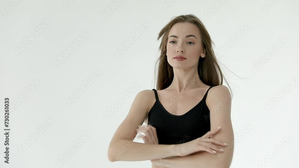 A beautiful slender girl in black leggings and a top with her hair down poses in a white studio. Slow motion A beautiful slender girl in black leggings and a top with her hair down poses in a white studio. Slow motion