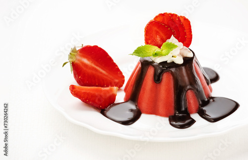 Strawberry mousse or strawberry panna cotta on a plate is decorated with chocolate, ricotta and fresh ripe strawberry slices on a white background. Healthy delicious dessert. Summer time