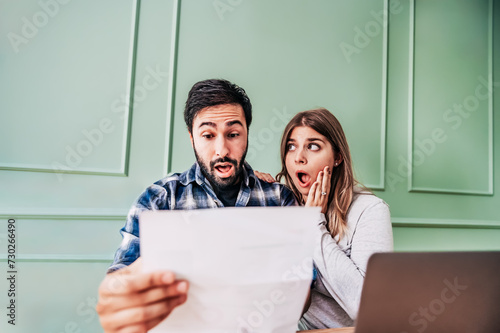 Stressed young couple checking bills, taxes and bank account balance at home  - Family at panicking debt and cost of living