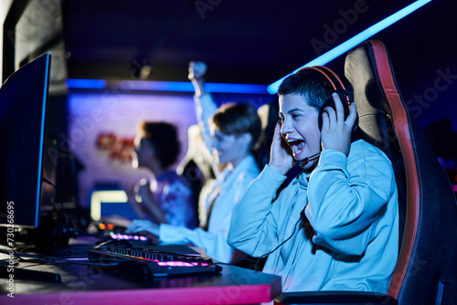 Valokuva focus on cheerful young woman winning game next to diverse female friends, cyber