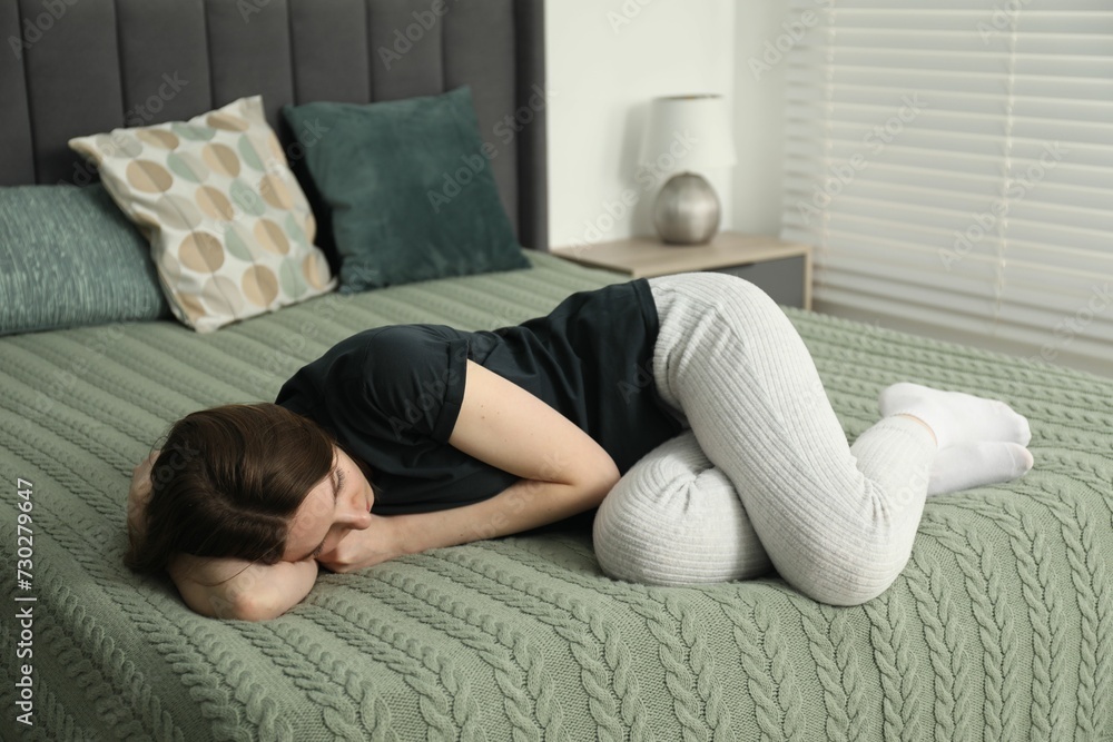 Sad young woman lying on bed at home Sad young woman lying on bed at home