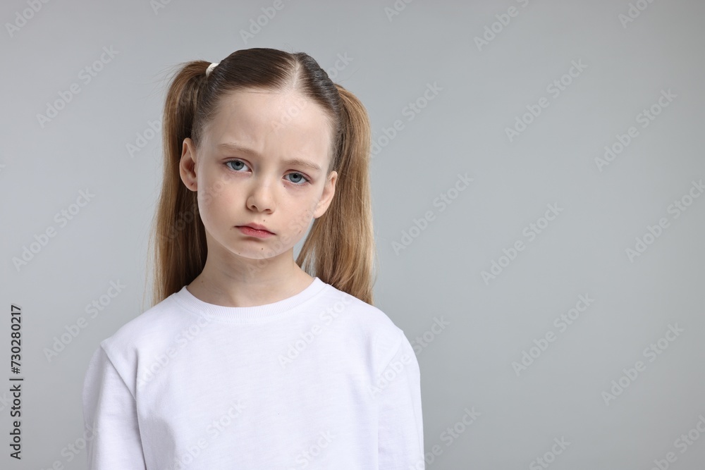 Fototapeta premium Portrait of sad girl on light grey background, space for text