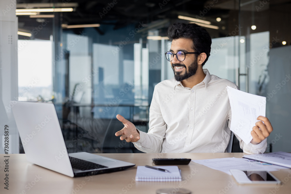 Confident indian businessman in office working on laptop with a warm smile Confident indian businessman in office working on laptop with a warm smile