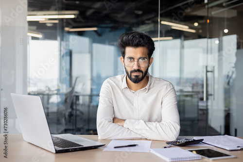 Confident indian businessman with beard working at desk in modern office