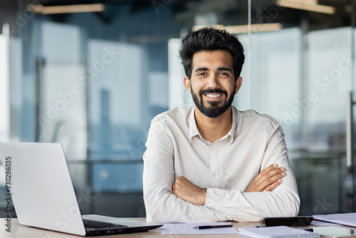 Confident indian businessman with beard working at office desk with laptop