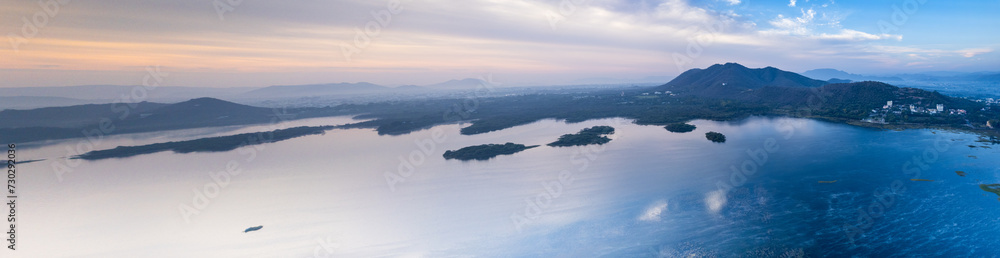 Aerial drone panoramic shot showing sunrise dawn dusk over aravalli hills lake pichola fateh sagar and cityscape in Udaipur, Chandigarh, Nainital showing famous tourist spot