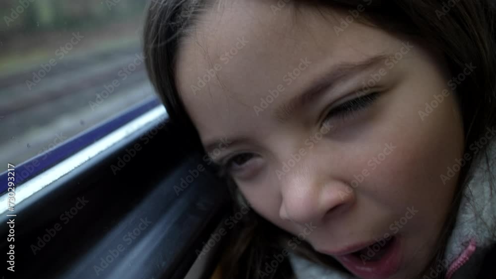Tired child yawning while traveling by train, little girl leaning on window feeling exhausted while on moving transportation Tired child yawning while traveling by train, little girl leaning on window feeling exhausted while on moving transportation