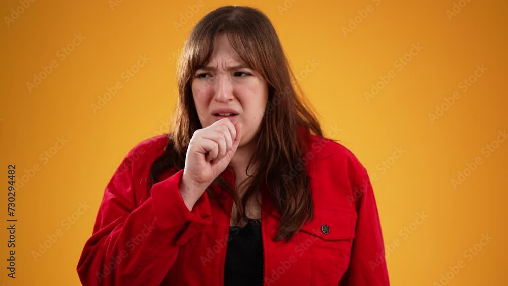 Portrait of young woman wearing red jacket 20s sick with cough and sore throat isolated on yellow background in studio with copy space in slow motion Portrait of young woman wearing red jacket 20s sick with cough and sore throat isolated on yellow background in studio with copy space in slow motion