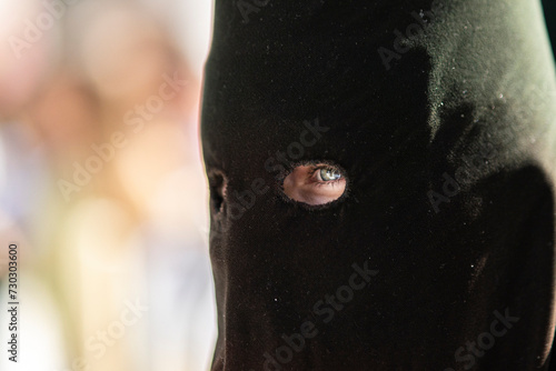 penitente con un cirio en la mano viendo los ojos a través de un capirote. photo