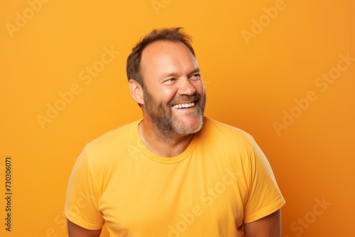 Portrait of smiling man in yellow t-shirt on orange background