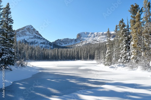 A photo capturing the snowy landscape with trees covered in snow surrounding a large body of water.