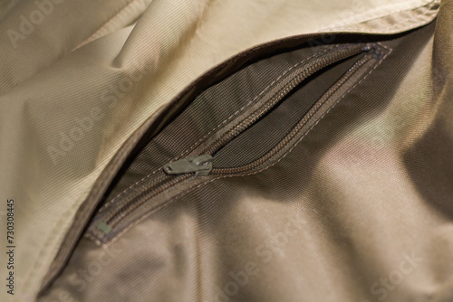 Zipper on beige workwear protective clothing in close-up.