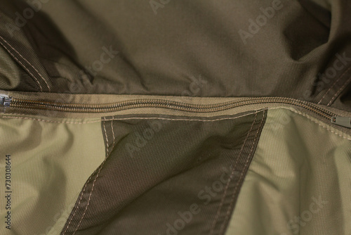Zipper on beige workwear protective clothing in close-up.