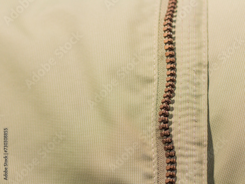 Zipper on beige workwear protective clothing in close-up.