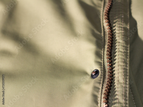 Zipper on beige workwear protective clothing in close-up.