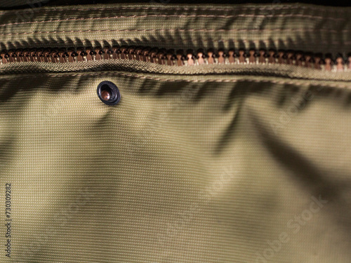 Zipper on beige workwear protective clothing in close-up.