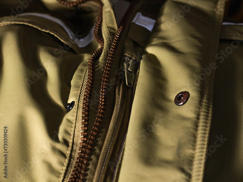 Zipper on beige workwear protective clothing in close-up.