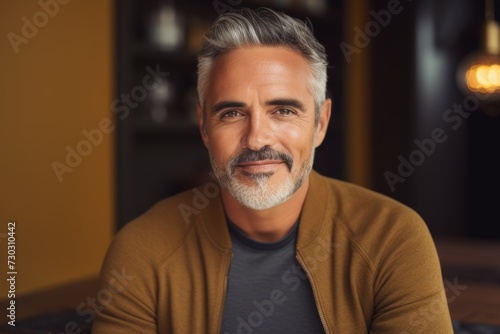 Portrait of handsome mature man looking at camera and smiling while sitting in cafe