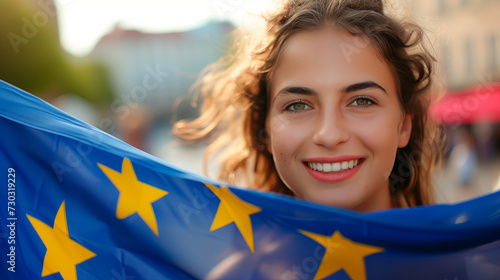 Young woman holding the EU flag, symbol of the European Union. Shallow field of view.