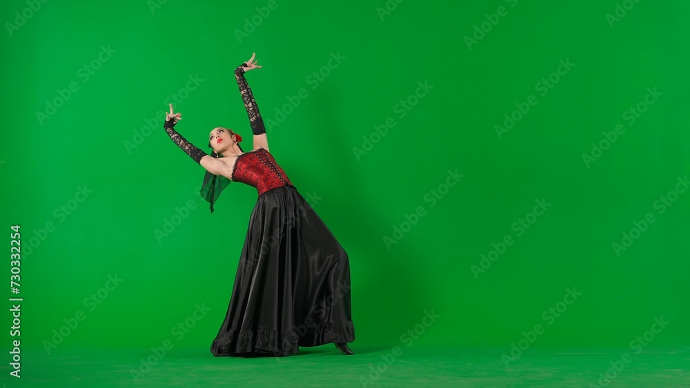 Fototapeta premium Woman dancer dancing on chroma key green screen. Female in flamenco style dress performs elegant spanish dance moves with her hands and body in the studio.