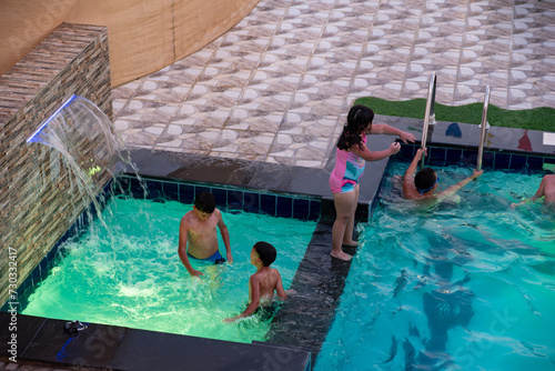 Kids and adult having wounderful time while swimming in the pool photo