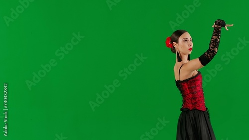 Woman dancer dancing on chroma key green screen. Female in flamenco style dress performs elegant spanish dance moves with her hands and body in the studio.