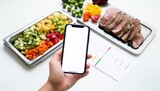 A blank screen phone placed next to high protein food plate, food delivery, diet, nutrition app concept