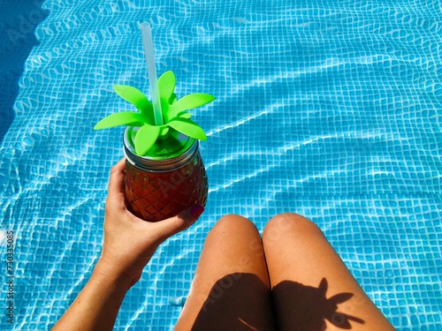 Woman in the pool holding a drinking jar shaped like a pineapple