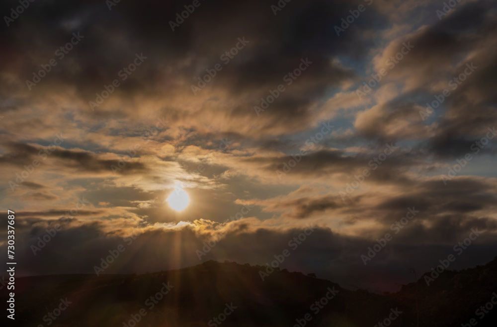 Sunset with sun rays between the clouds, mystical scene with space for text