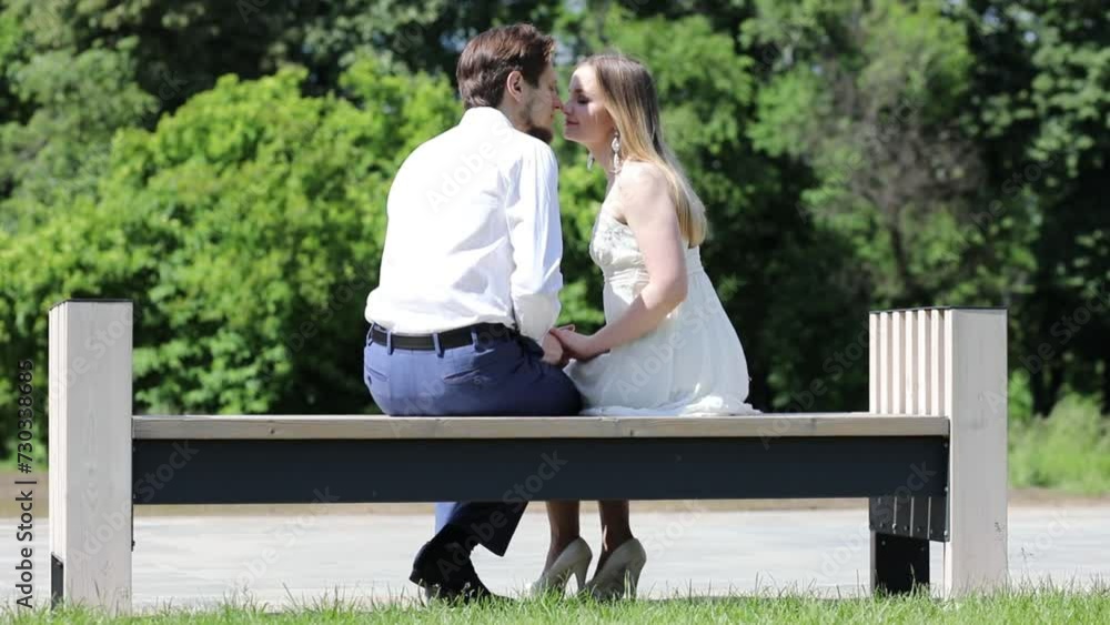 Woman and man sits on bench in park with lilac at sunny day, slow motion Woman and man sits on bench in park with lilac at sunny day, slow motion