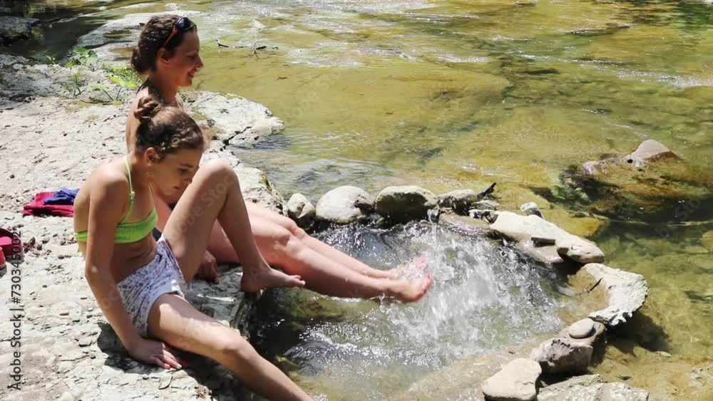 Woman with her daughter wet feet in cold mountain river, slow motion Woman with her daughter wet feet in cold mountain river, slow motion