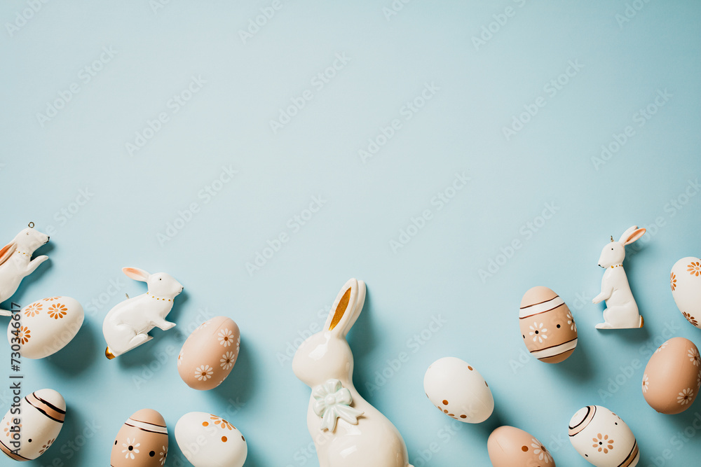 Floral painted Easter eggs in natural colors, decorative rabbits on pastel blue background. Happy Easter card.